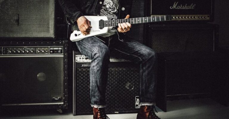 Amplifier - Man Sitting on Guitar Amplifier Playing Electric Guitar