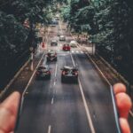 System - Forced Perspective Photography of Cars Running on Road Below Smartphone