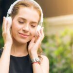 Headphones - Woman Wearing Black Sleeveless Dress Holding White Headphone at Daytime