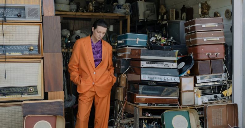 Turntables - A Woman in Orange Suit Standing in a Store with Stacks of Turntables